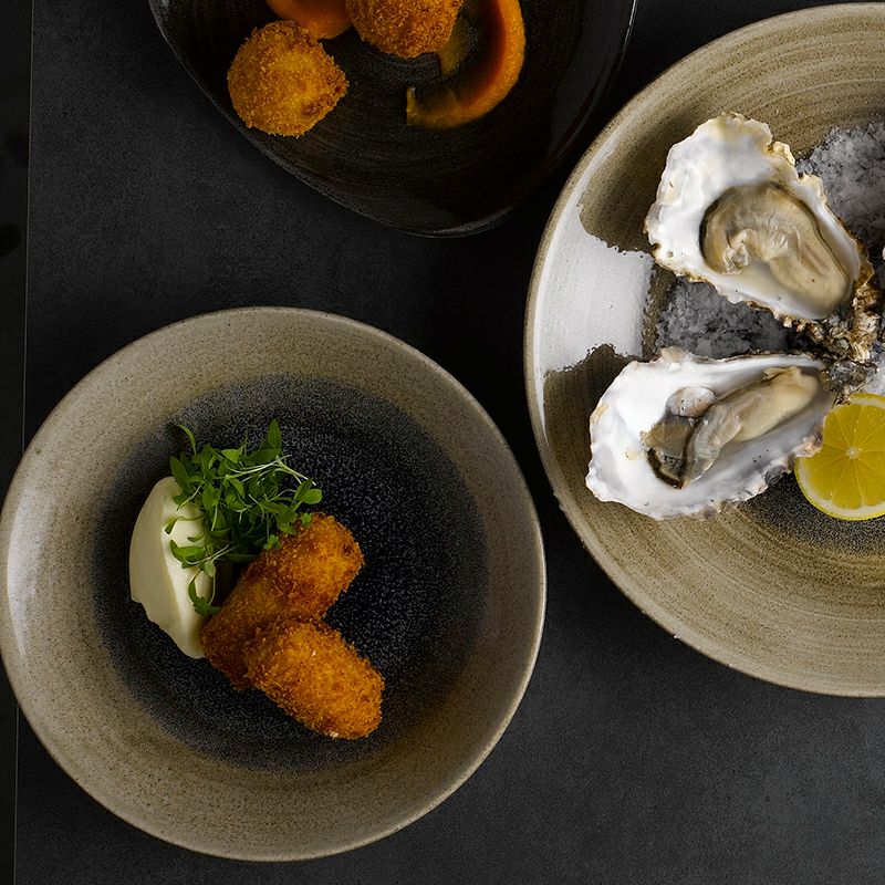 和食器にも通じる渋い色味のストーンキャストの正円形の丸皿。刷毛目がワンポイント。